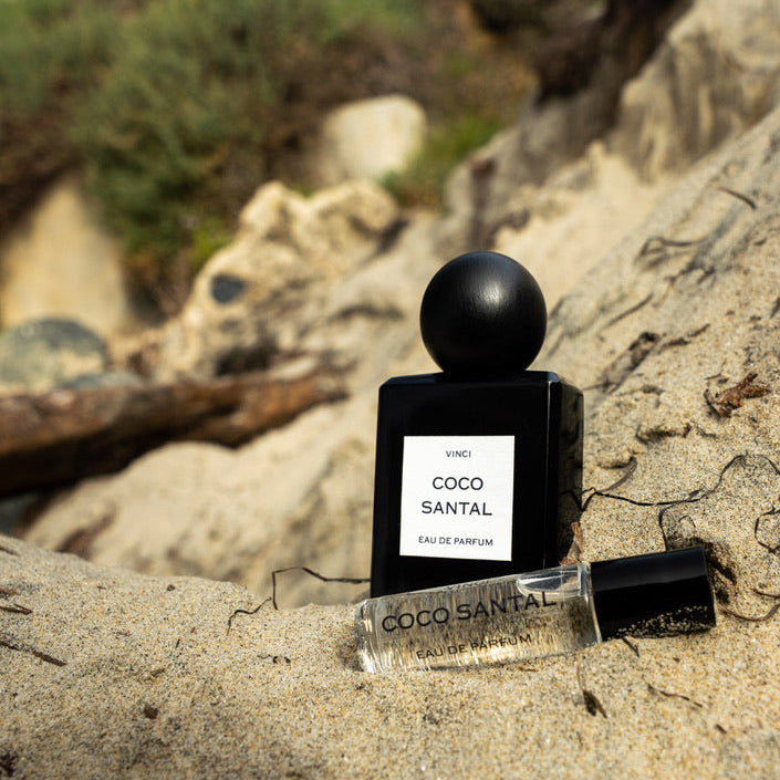 Coco Santal perfume bottle on a rocky beach